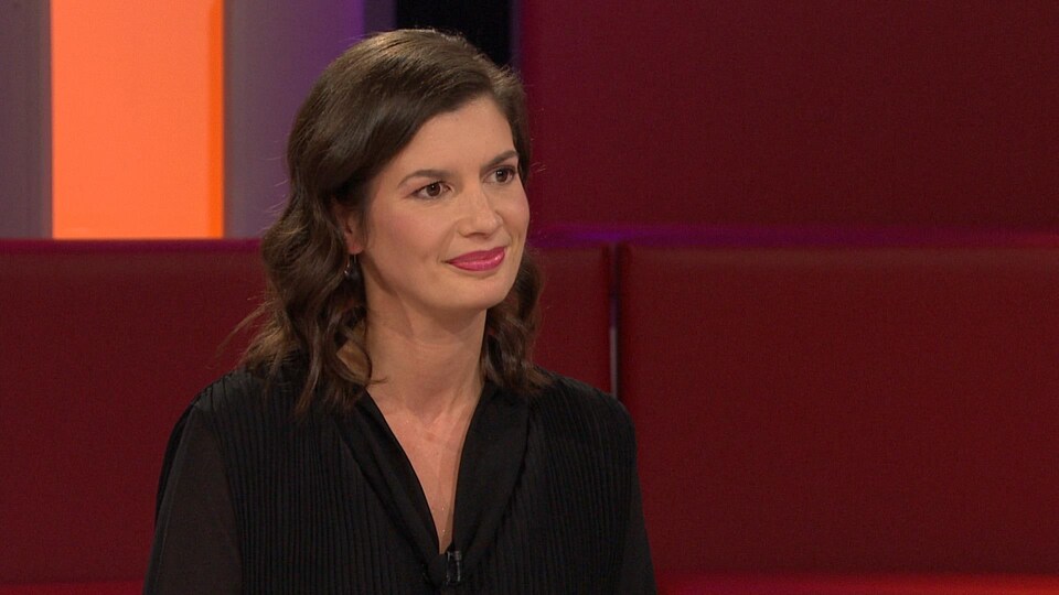 Plan rapproché de Geneviève Guilbault assise dans un décor de plateau de télévision.