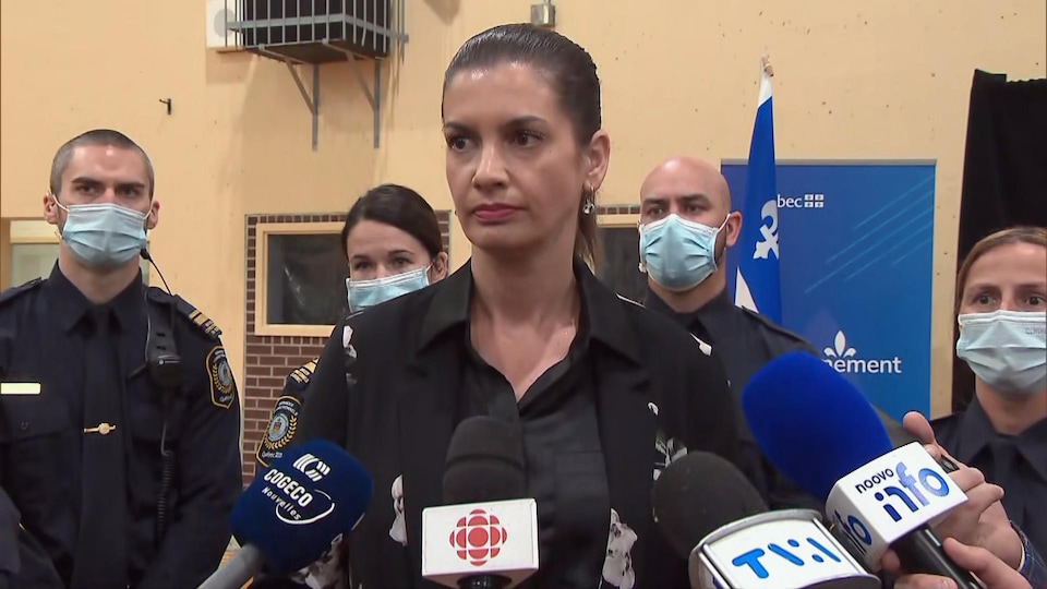 Geneviève Guilbault lors d'une mêlée de presse à l'Établissement de détention de Québec; elle est entourée d'agents des services correctionnels qui portent un couvre-visage.