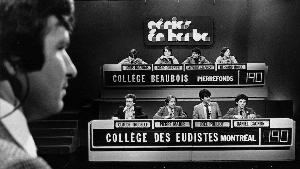 Dans un studio de télévision, l'animateur Michel Benoît fait face aux quatre participants du collège Beaubois de Pierrefonds et à ceux du Collège des Eudistes de Montréal.
