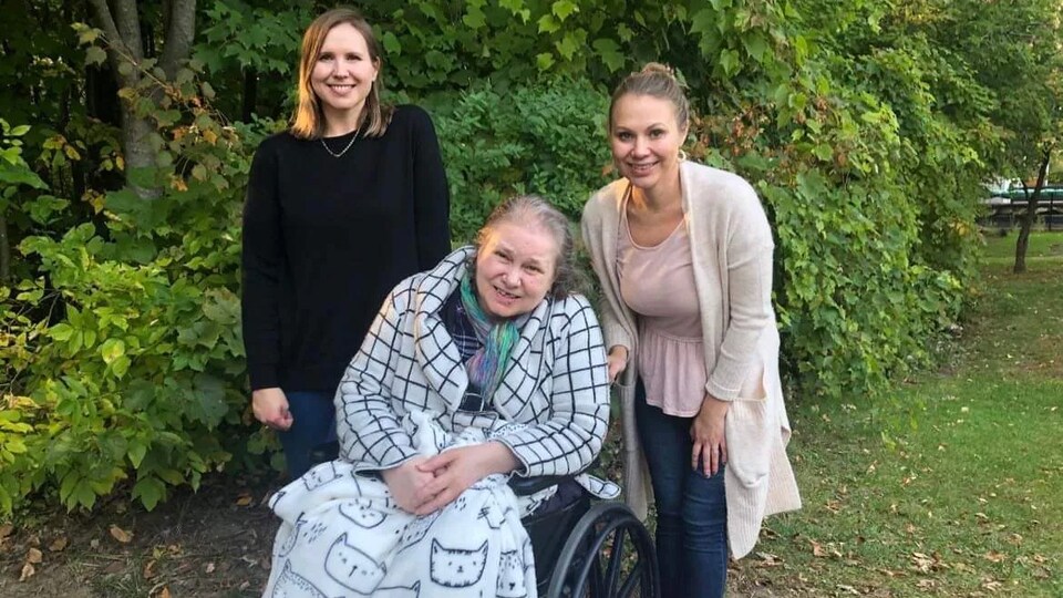 Trois personnes posent pour une photo, l'une d'elles est en fauteuil roulant.