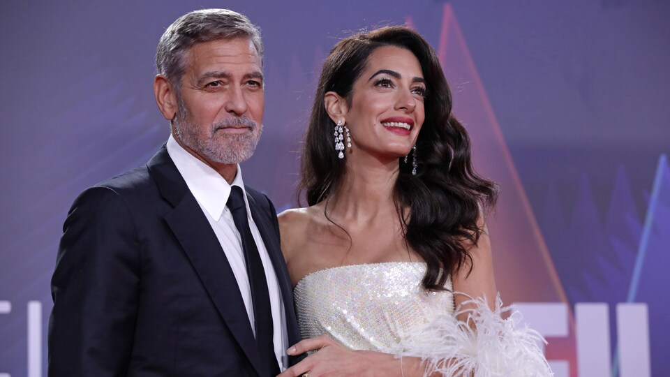 Un homme et une femme posent sur un tapis rouge.