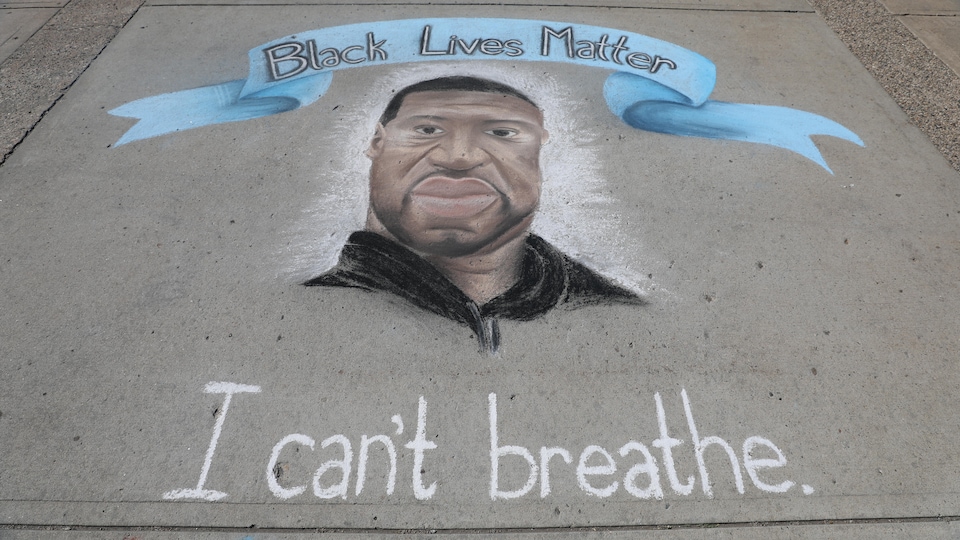Un dessin de George Floyd à la craie sur le trottoir avec un bandeau Black Lives Matter (la vie des Noirs a de la valeur) et le slogan I can't breathe (je ne peux respirer).