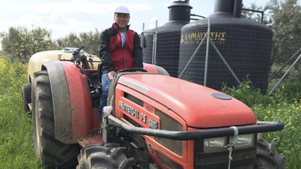 George Pananos sur un tracteur à l'oliveraie.