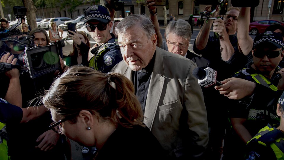 Entouré de policiers et de journalistes, le cardinal George Pell.