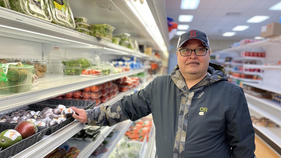 Portrait de George qui porte une casquette dans une rangée d'épicerie.