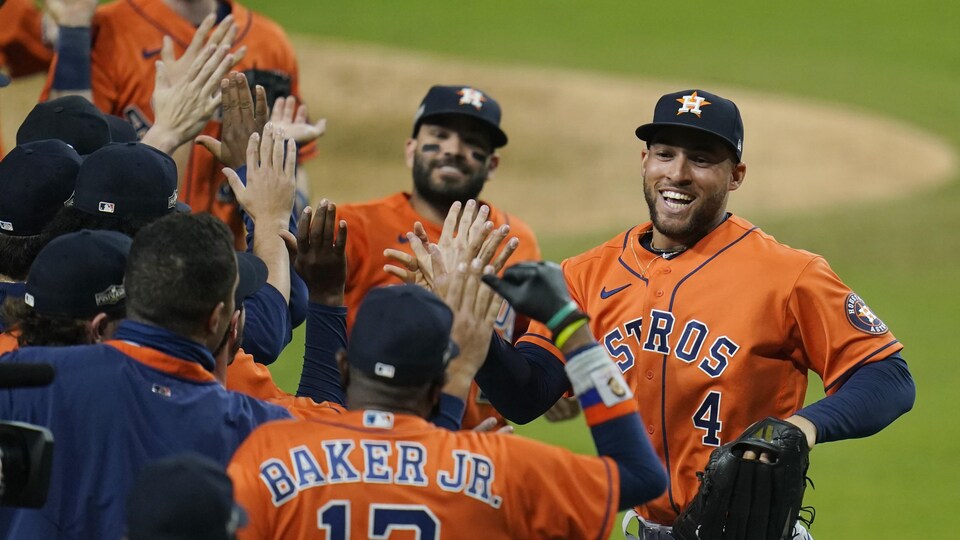George Springer donne la main à ses coéquipiers en file après une victoire.
