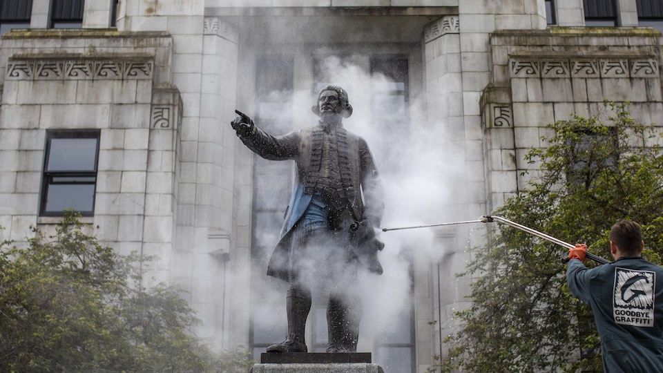 La Statue de George Vancouver est nettoyée aprèès avoir été vandalisée avec de la peinture à l'extérieur de la Mairie de Vancouver, le 11 juin 2020.
