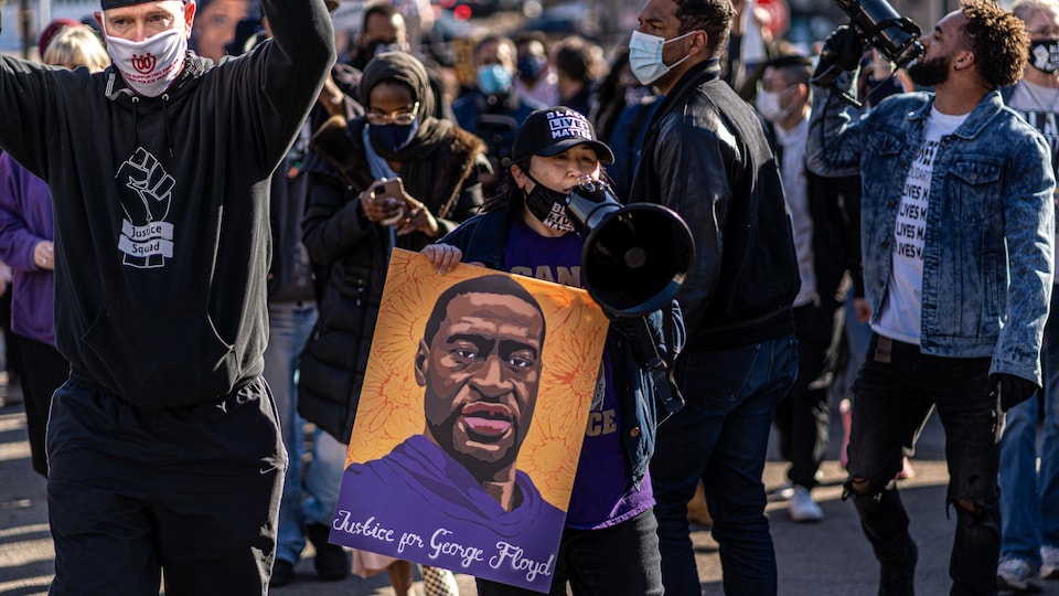 Les manifestants défilent en brandissant des pancartes à l'effigie de George Floyd.