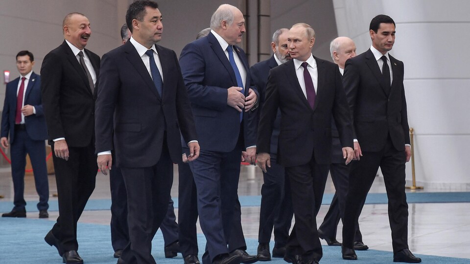Un groupe d'hommes marche dans une salle.