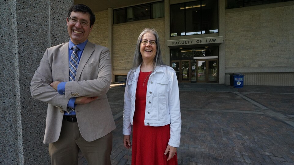 M. Heckman et Mme Turnbull souriant devant le bâtiment qui abrite la faculté de droit.