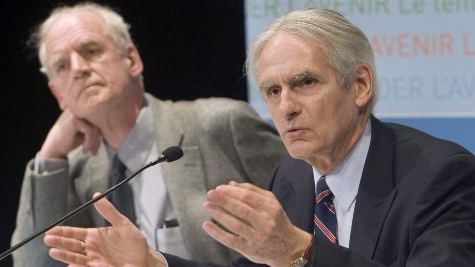 Charles Taylor et Gérard Bouchard assis derrière une table lors du dévoilement de leur rapport de la commission sur les accommodements raisonnables en mai 2008.