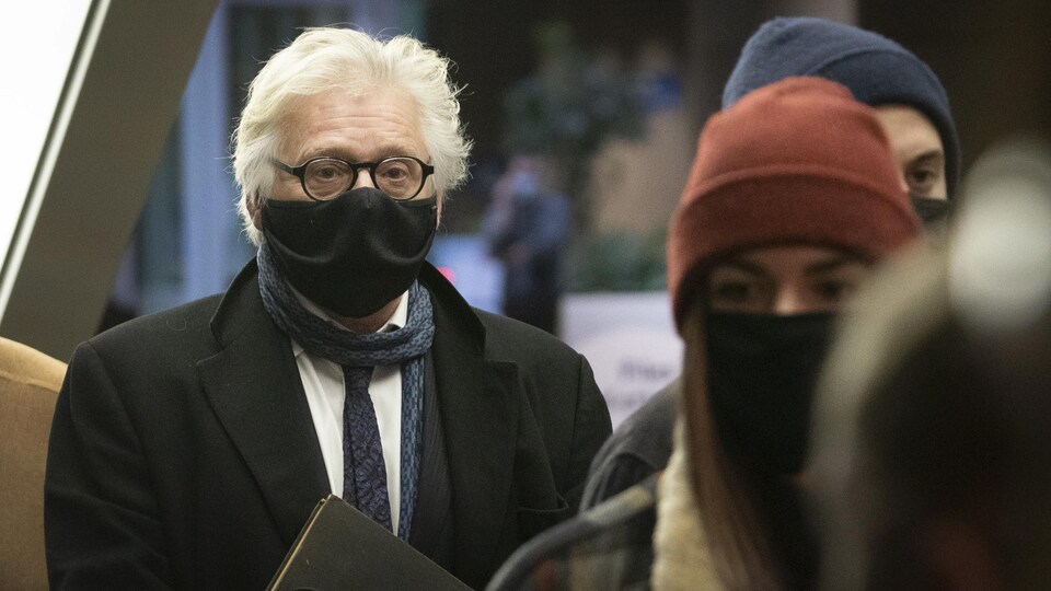 Gilbert Rozon portant un masque dans un corridor du palais de justice de Montréal.