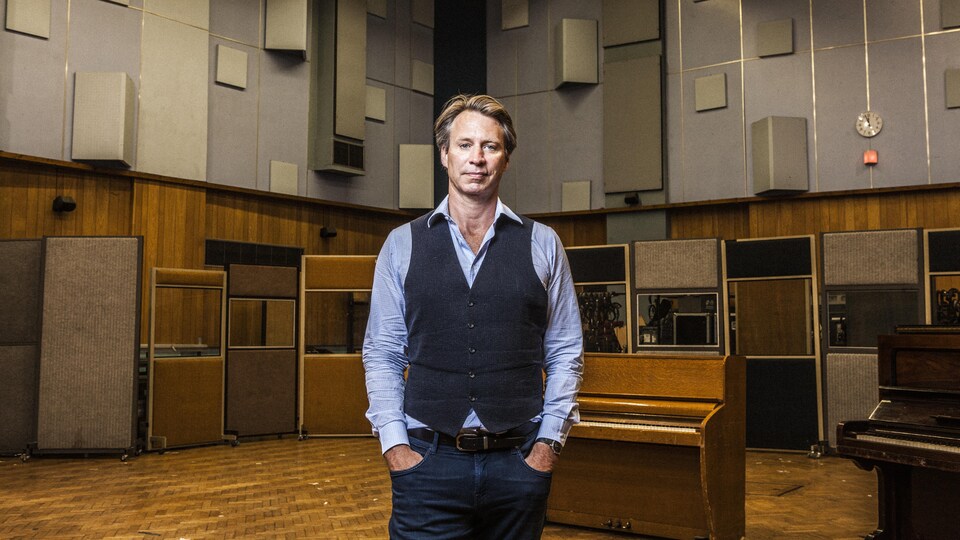 Un homme pose dans un studio d'enregistrement de musique.