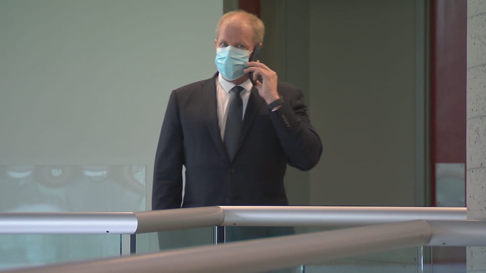 Vêtu d'un complet, le psychiatre tient un cellulaire dans le palais de justice de Québec.