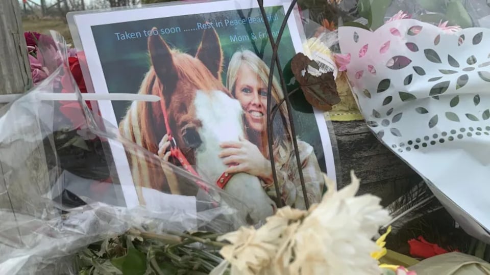 une photo de Gina Goulet flattant un cheval placé au milieu des fleurs lors d'une vigile qui a suivi la tuerie du 18 et 19 avril 2020.
