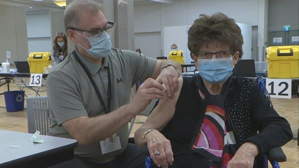 Une femme à l'épaule découverte reçoit un vaccin.