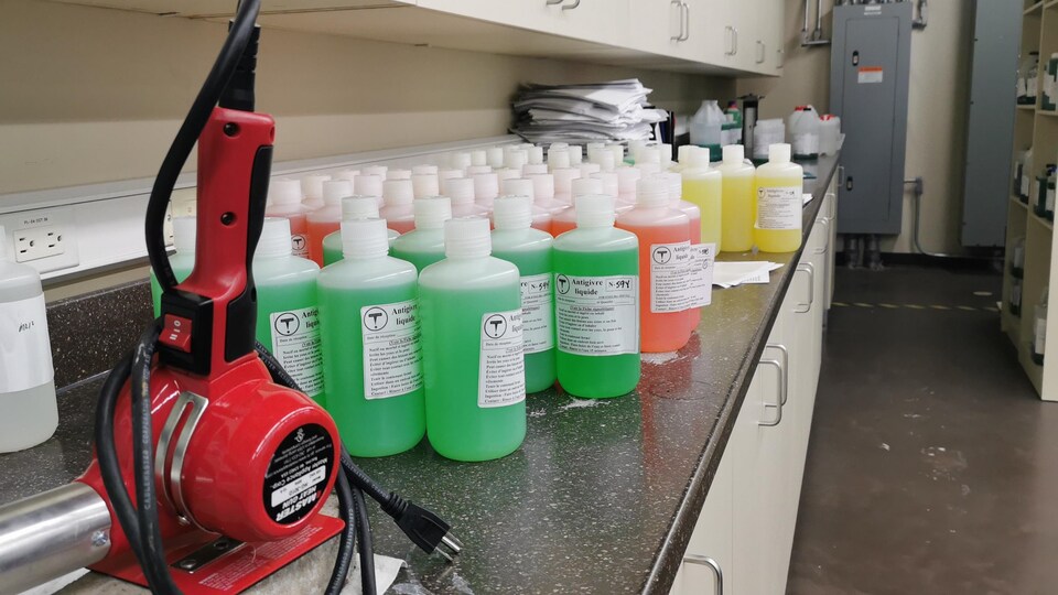 Des bouteilles de liquide vert, rouge et jaune sont sur une table de laboratoire.
