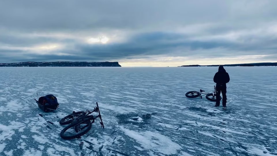 Une personne debout sur la glace d'un lac.