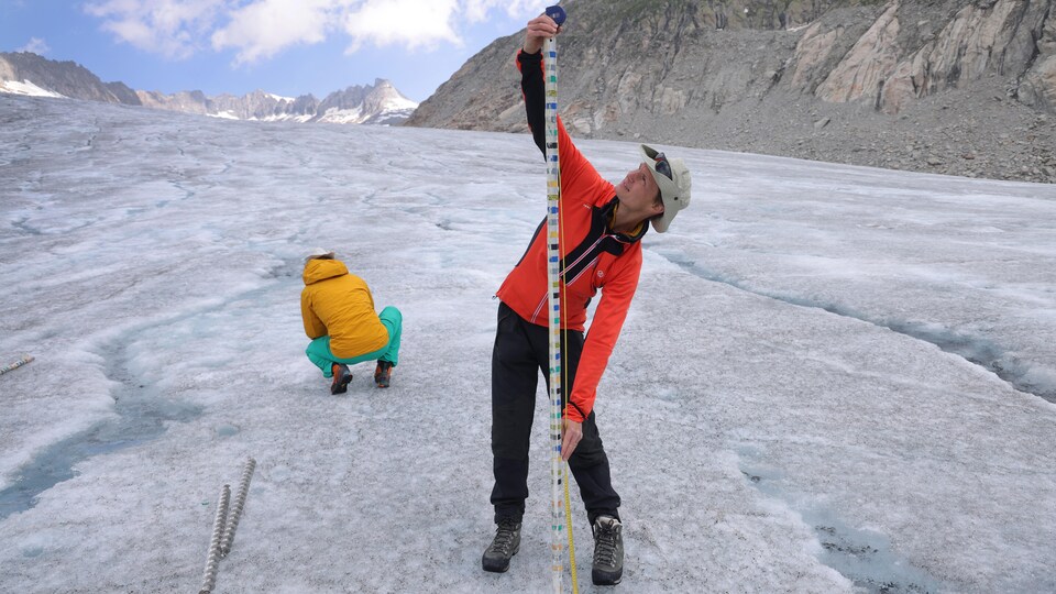 Deux hommes se tiennent sur un glacier. 
