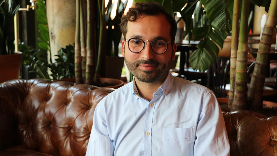 A man wearing glasses and smiling, in an apartment.