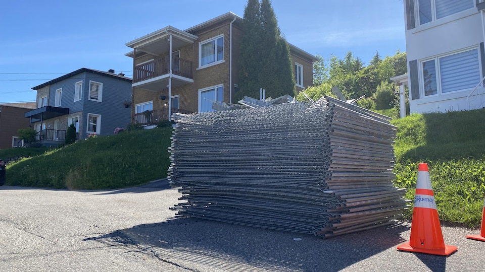 Une rue avec des clôtures métalliques empilées devant une maison.