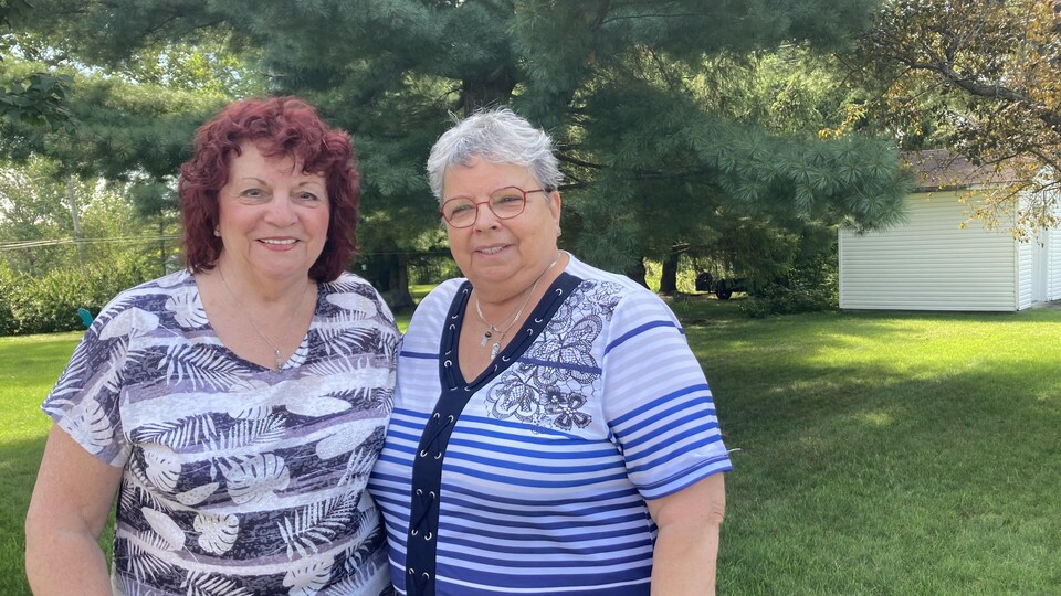 Deux femmes posent dans une cour arrière.