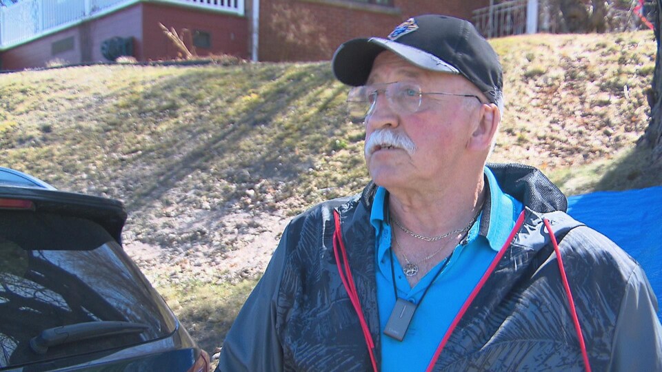A man gives a lecture in front of his house.