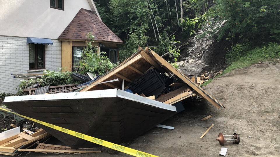 Un bâtiment est renversé au sol à côté d'une maison.