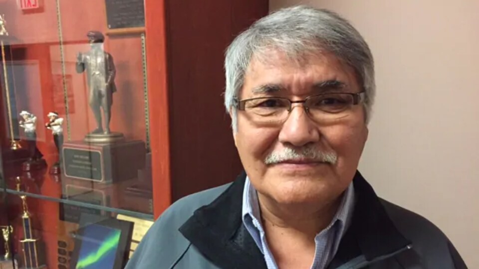 Paul Andrew, in front of a shelf containing trophies.