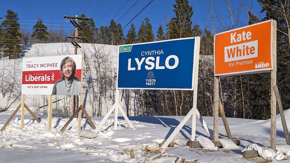 Des affiches du Parti libéral, du Parti du Yukon et du Nouveau Parti démocratique devant une bute enneigée, le 18 mars 2021.