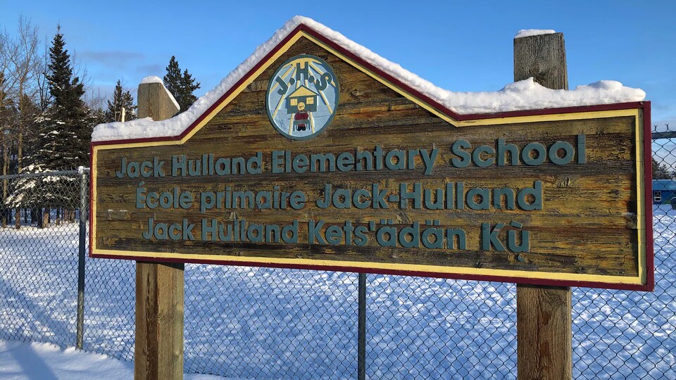 Panneau de bois en trois langues annonçant l'École primaire Jack-Hulland, à Whitehorse, à l'hiver 2022.
