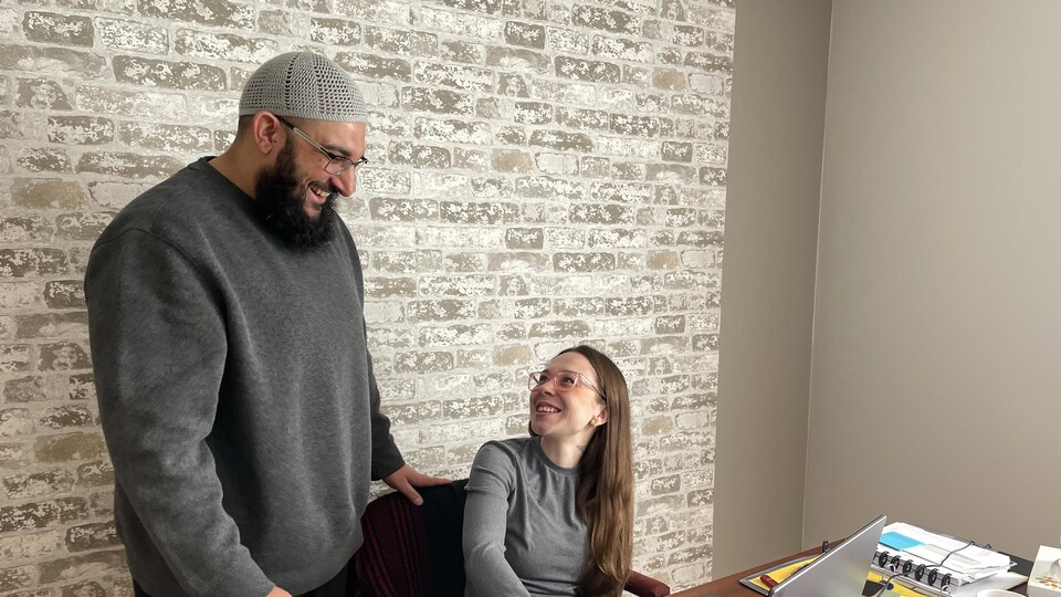 Ali Farook regarde une collègue assise à un bureau.