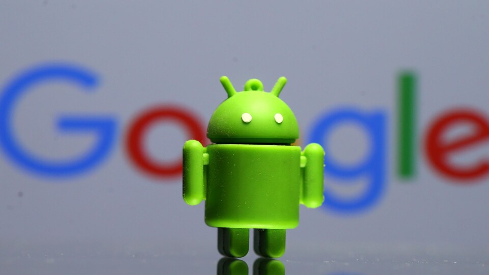 Une figurine de la mascotte du logiciel mobile Android, devant le logo de Google