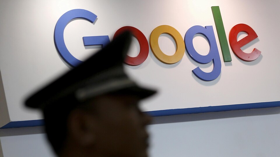 La silhouette floue de profil d'un homme aux traits asiatiques portant une casquette de policier devant le logo de Google.
