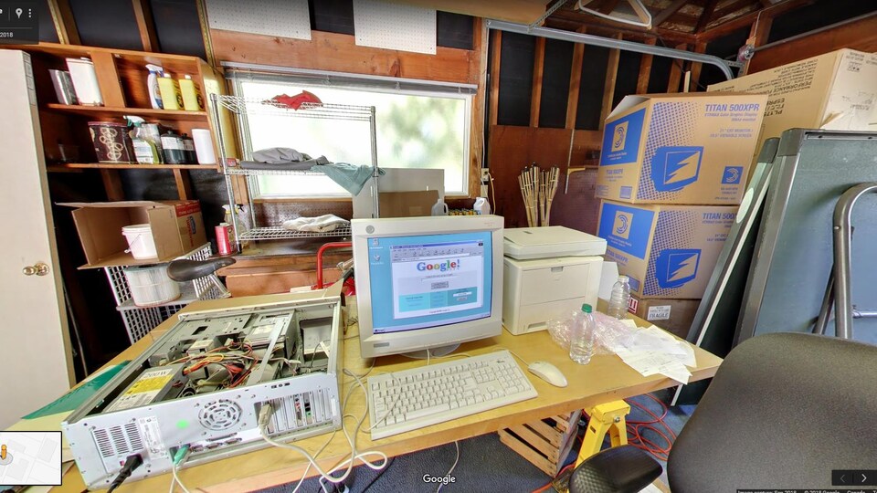 Une photo montrant l'intérieur d'un garage en désordre, au centre duquel est posé un bureau. Un écran d'ordinateur cathodique affichant la page d'accueil de Google de 1998 est posé sur le bureau.