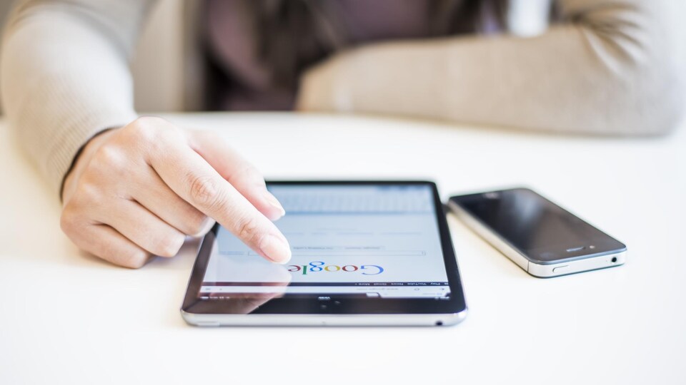 Une femme utilise le moteur de recherche Google sur une tablette numérique.