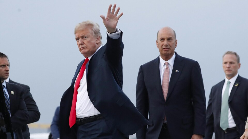 Donald Trump salue de la main, aux côtés de Gordon Sondland.