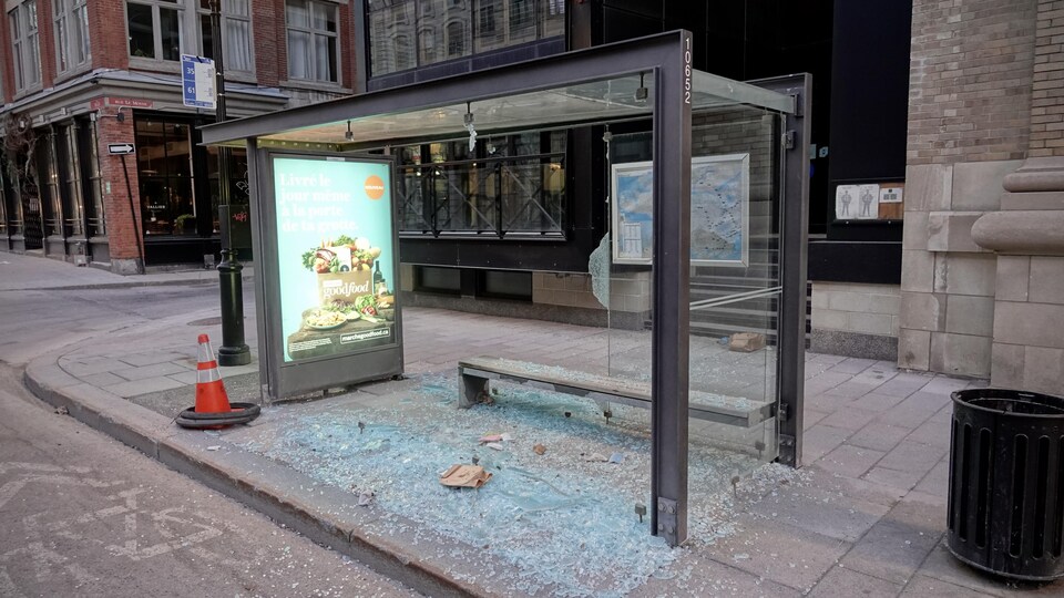 Un abribus dont les vitres ont été éclatées. Le sol est couvert d'éclats de verre.