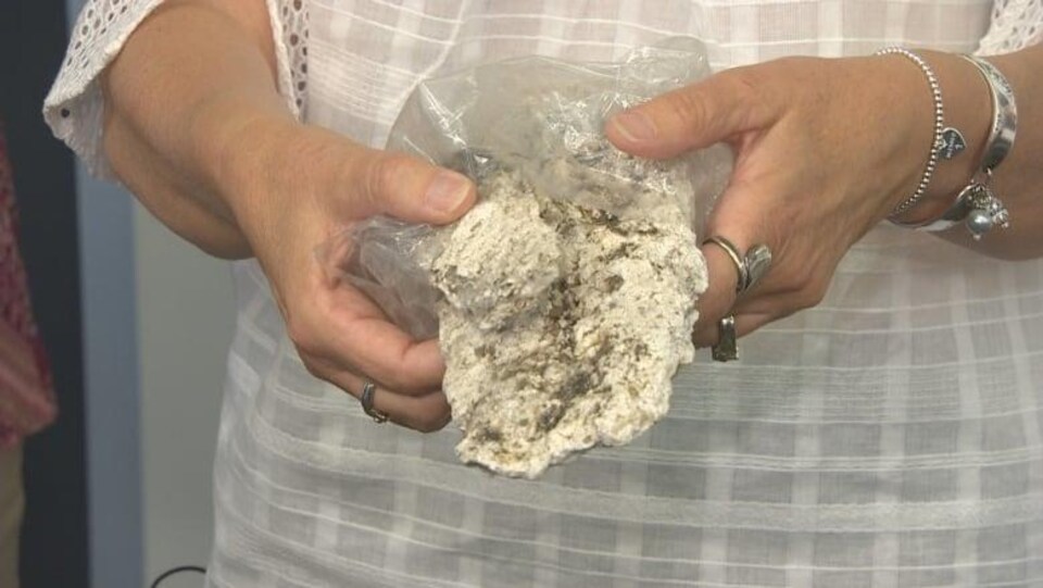 Une femme tient dans ses mains de la graisse solidifiée qui ressemble à du béton.