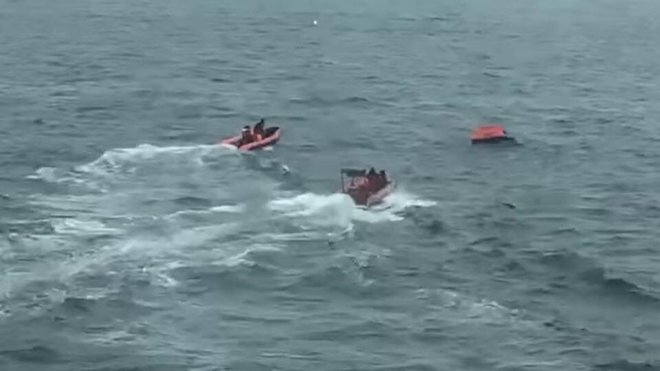 Deux petits bateaux de sauvetage sur l’eau naviguent en direction d’un radeau. 