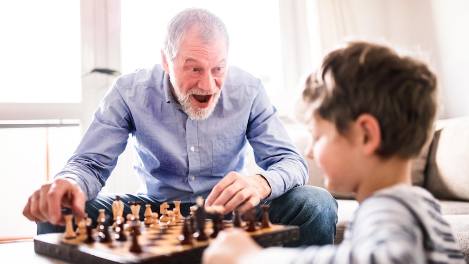 Un grand-père et son petit-fils jouent aux échecs.