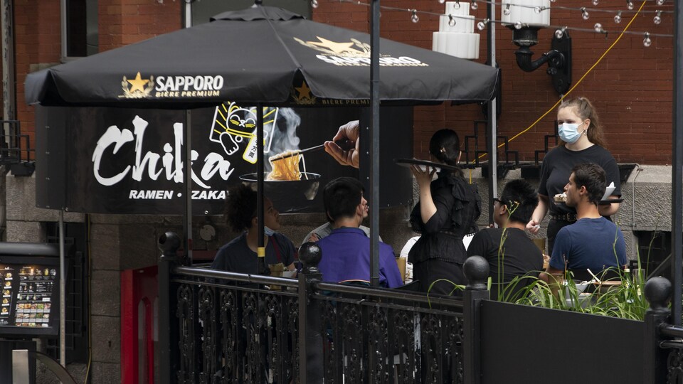 Des gens autour d'une table sur une terrasse d'un établissement de la Grande Allée, à Québec.