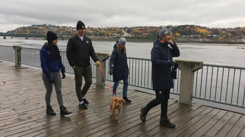 Deux hommes et deux femmes marchent en bordure du Saguenay. Un des deux hommes tient un chien en laisse.