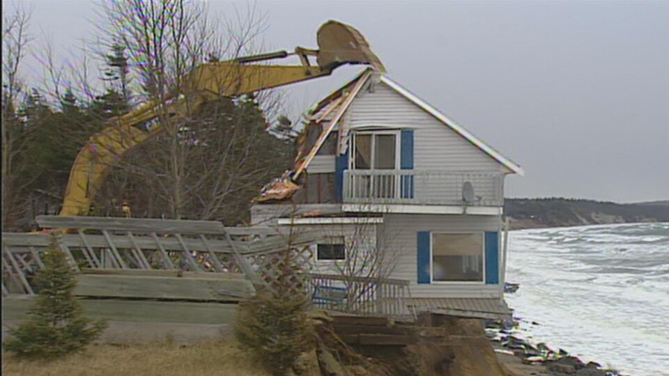 Une pelle mécanique s'apprête à détruire une maison à Sept-Îles.