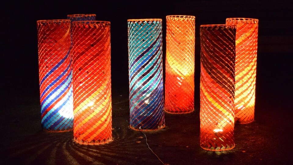 Une oeuvre d'art composée de sept colonnes réalisés avec des matériaux recyclés et éclairées par une lumière comme des lampions.