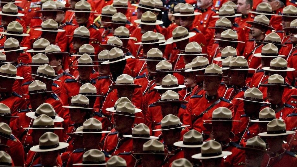 De nombreux agents de la Gendarmerie royale du Canada sont debout en uniforme rouge lors d'une cérémonie.