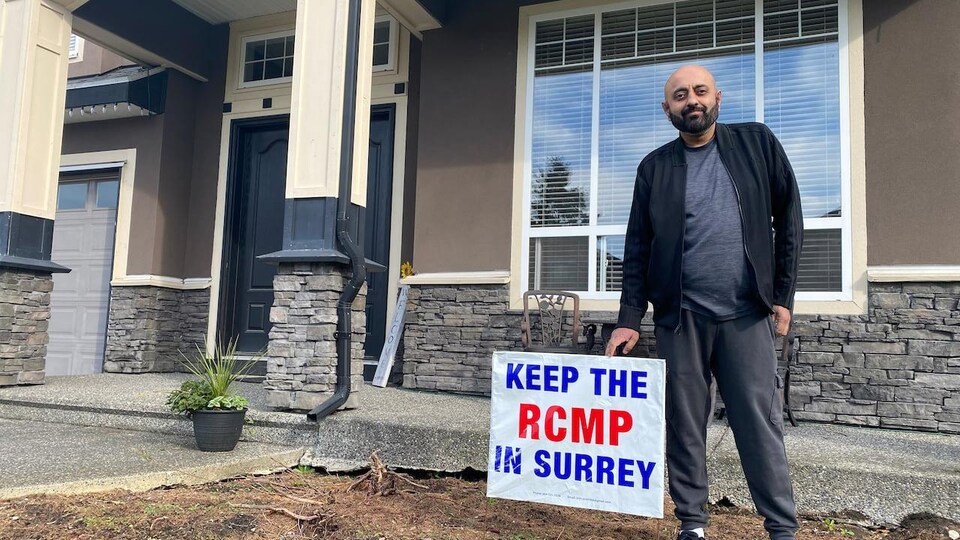 Ben Cooner pose avec son affiche Gardons la GRC à Surrey (Keep RCMP in Surrey, en anglais).