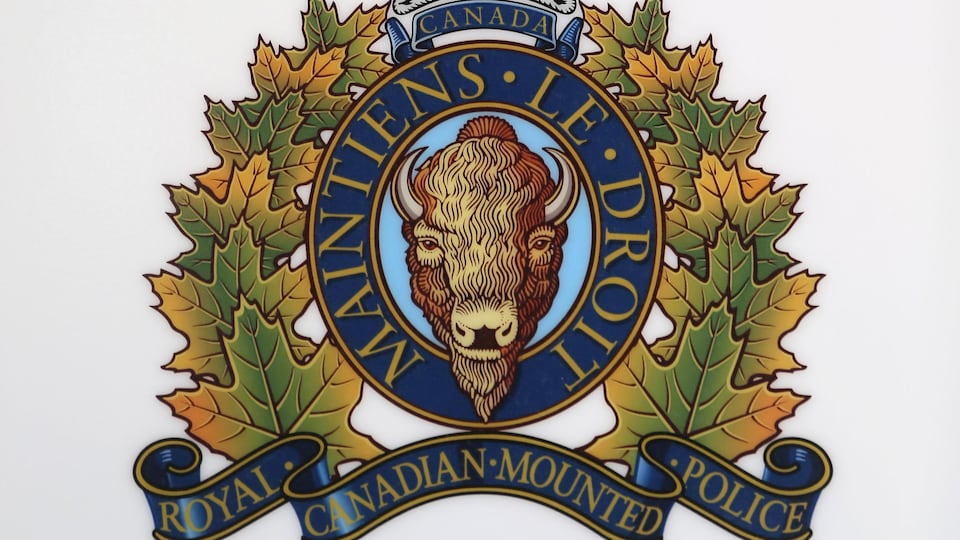 Armoiries de la Gendarmerie royale du Canada montrant un buffle couronné et ceinturé de feuilles d'érable. L'écusson porte la devise du corps policier : « Maintiens le droit ».