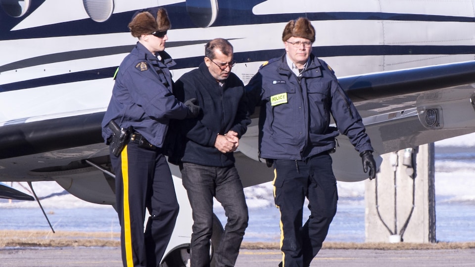 Des agents de la Gendarmerie royale du Canada escortent l'un des suspects arrêtés dans le cadre de l'opération Collecteur.