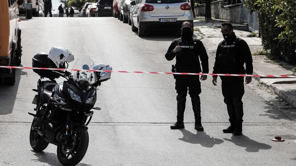 Des policiers grecs bloquent une rue, avec une moto à leur droite.